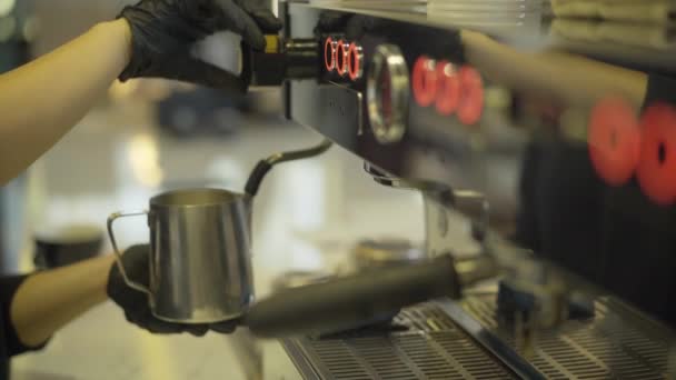 Side view of unrecognizable Caucasian barista beating milk using professional coffee machine. Female hands preparing tasty hot drink in restaurant or cafe. — Stock Video