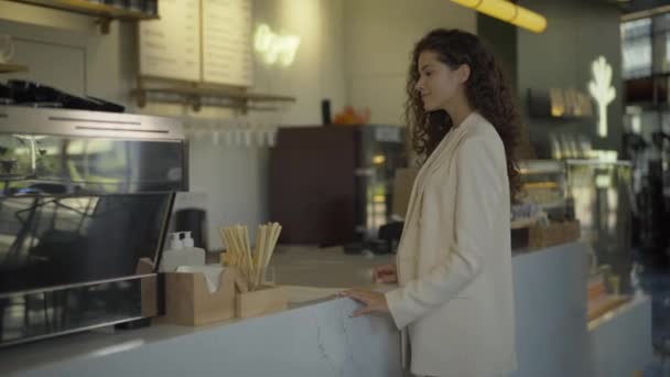 Bella donna d'affari fiduciosa che prende ordine nel caffè e se ne va con due tazze di caffè. Ritratto di donna caucasica bruna di successo che compra caffè-to-go nel ristorante per pranzo. — Video Stock