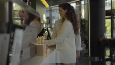 Genç ve çok ırklı bir çiftin kafede düzen kurup gidişinin yan görüntüsü. Beyaz tenli yakışıklı bir adam ve güzel bir kadın restoranda yemek siparişi veriyor..