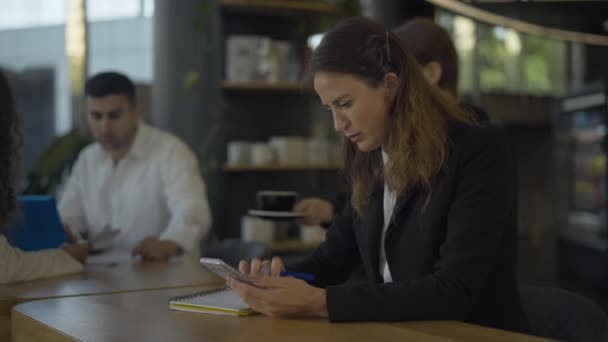 사업 계획서를 작성하고 전화 통화를 하고 바텐더가 뒤에서 점심을 먹는 사람들에게 주문을 하는 성공적 인 여성의 측면. 쉬는 시간에 근무하는 여성 CEO. — 비디오