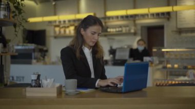 Kendine güvenen iş kadını dizüstü bilgisayarda klavye kullanıyor ve kameraya gülümsüyor. Tatil sırasında Kafe 'de çalışan beyaz kadın CEO' nun portresi. Girişimcilik kavramı.