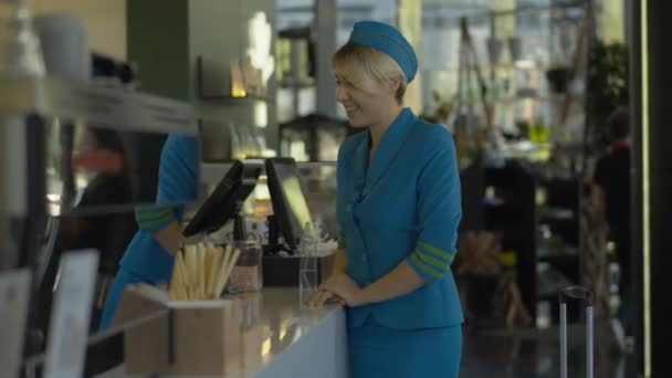 Портрет кавказской стюардессы в форме, покупающей кофе на вынос и уходящей. Позитивно улыбающаяся молодая женщина берет чашку кофе у баристы и уходит в кафе. Концепция профессии. — стоковое видео