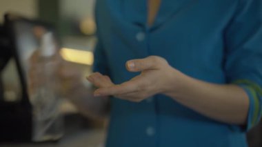 Mavi üniformalı tanınmayan bir hostes dezenfektanla elleri dezenfekte ediyor. Dezenfektan sıkan ve avuçlarını ovuşturan beyaz bir kadın. Covid-19 salgını sırasında turizm güvenliği.