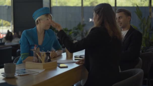 Positives kaukasisches Paar im Gespräch mit einer Stewardess im Café. Fröhlich entspannte Freunde treffen sich im Restaurant und plaudern. Lächelnde selbstbewusste Stewardess ruht sich vor dem Flug aus. — Stockvideo