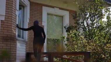 Gizemli bir kukuletalı figür sessizce evin dışından dolaşır, gizlice pencereye girmeye çalışır.