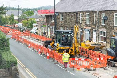 Roadworks kazıcı, engelleri ve işçi ile bir sokakta.