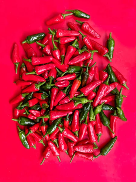 Piros és zöld chili paprika. Halom piros háttér. — Stock Fotó