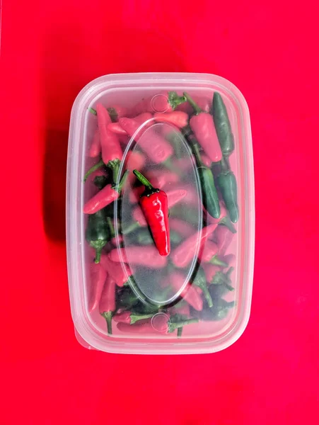 Piros és zöld chili paprika műanyag tartályban. — Stock Fotó