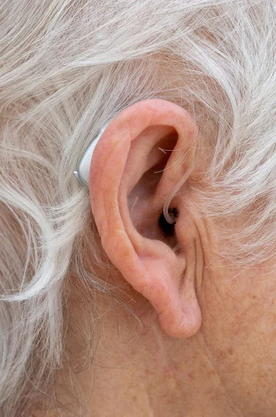 Atrás do ouvido aparelho auditivo sendo usado pelo aposentado . Fotos De Bancos De Imagens Sem Royalties