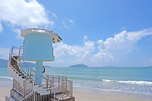 Mavi ve beyaz cankurtaran kulesi, plaj ve okyanus dalgası ile