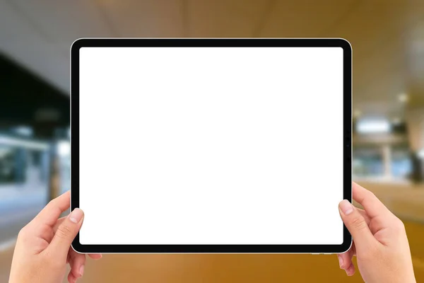 The human two hands holding white screen mockup tablet computer in airport terminal traffic station