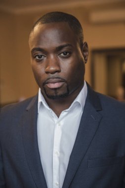 Kameraya bakarak ciddi bir yüz ifadesiyle genç işadamı önden görünüm.