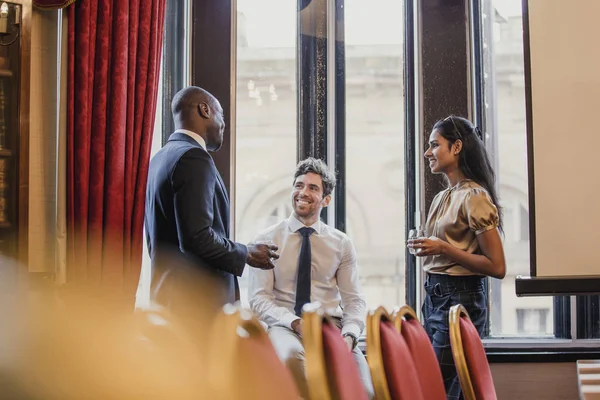 Side view of three business people, standing, talking after a business conference.