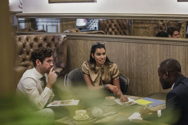 Side View of three business people having a little business meeting and talking over some coffee.