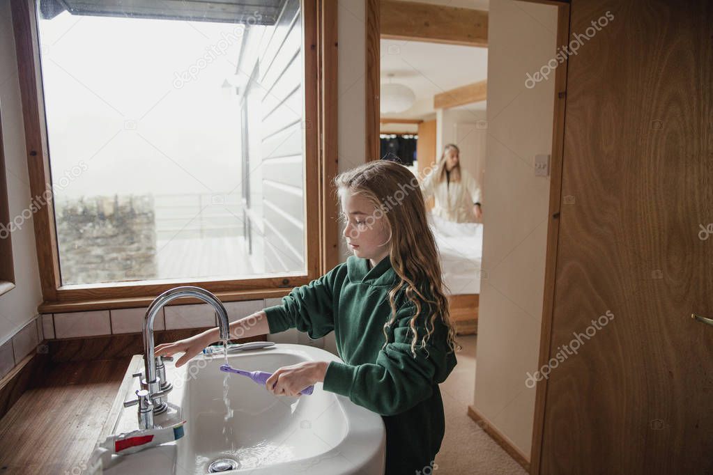 Little girl dressed in a school uniform brushing her teeth before going to school.