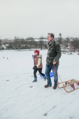 Küçük kız ve babası onların yol kızaklarımız ile karda büyük bir tepeye yapıyoruz.