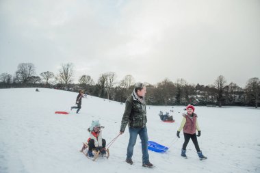 Onun kızı ile karda kızakla dışarı adamdır. 