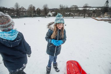 Küçük kız karda arkadaşları ve ailesi ile eğleniyor. 