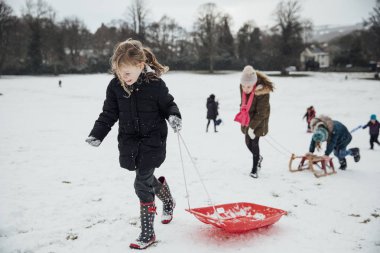 Bir tepeye karda bir kızak yarışı için koşu grubu küçük kızlar.