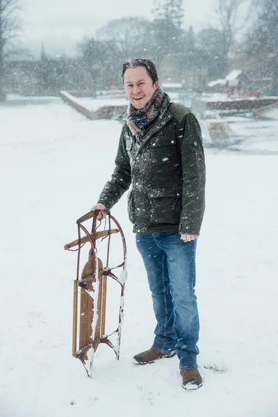 Mature Man Smiling Camera While Standing Outdoors Snow Holding Sleigh — Stock Photo, Image