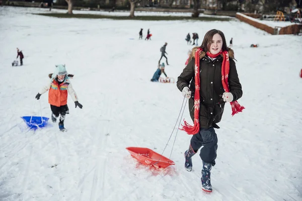 Group Young Friends Sledding Together Snow Running Back Hill Sleds — Stock Photo, Image