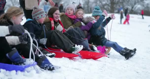 孩子们排在雪地上雪橇上的山顶上 他们被父母推倒在山上 — 图库视频影像