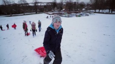 Küçük çocuk ve arkadaşları büyük bir tepe kızak yarışı için karda yürüme.