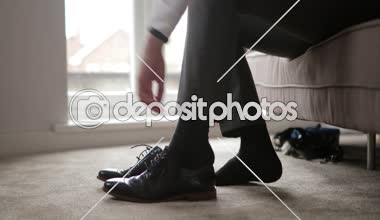Yüzey düzey görünümü resmi ayakkabılarında koyarak ve onları bağlayan unrecognisable erkek.