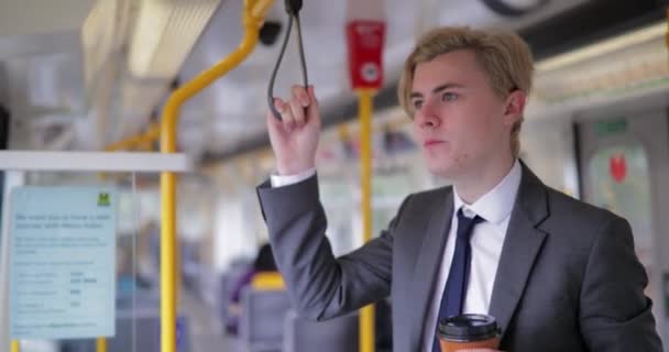 交通機関の彼のモードとして 鉄道を使用しながら立っている青年実業家の側面図です 通知を確認する彼のポケットにスマート フォンを取得 — ストック動画