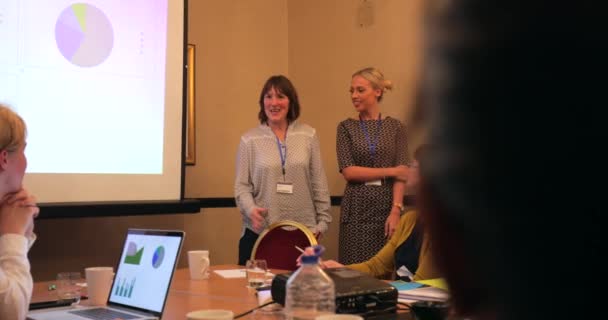 Par-dessus l'épaule d'un groupe de gens d'affaires qui posent des questions aux présentateurs d'une présentation dans le cadre d'une conférence .