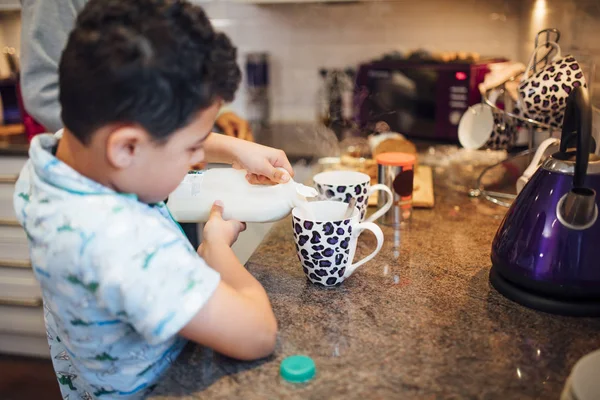 Мальчик Наливает Молоко Кружку Заваривая Чай Отцом Дома — стоковое фото