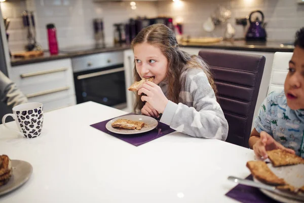 少女は家で彼女の家族と一緒に朝食をとりながらトーストのかみ傷を取っています — ストック写真