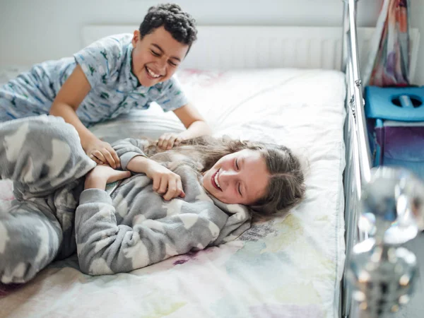 少年と彼の姉が自宅のベッドの上の Playfighting — ストック写真