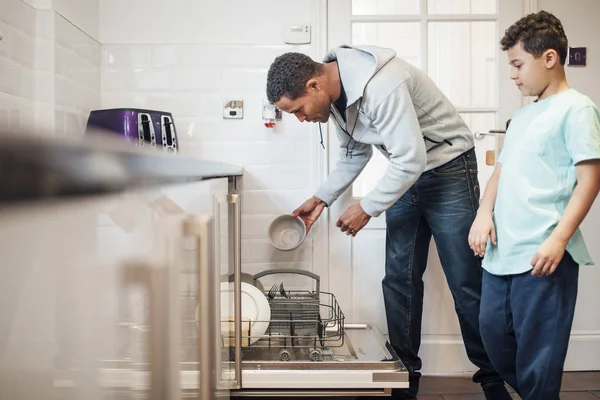 Взрослый Мужчина Загружает Посудомоечную Машину Домой Сын Наблюдает Ним — стоковое фото