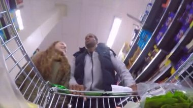 Küçük kız babası gıda bir süpermarkette alışveriş yapmak yardımcı oluyor. Listeye ararken arabası itiyor.