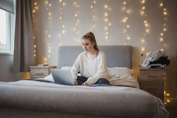 Genç Kadın Yatağında Bir Dizüstü Bilgisayar Kullanarak Oturuyor — Stok fotoğraf