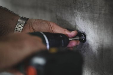 Birlikte bazı mobilya koymak için bir ışık yardımıyla matkap kullanan bir adam çekim kadar kapatın. 