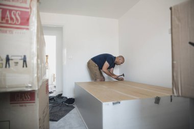 Olgun adam bir gardırop birlikte yeni bir ev bir yatak odasında koyuyor.