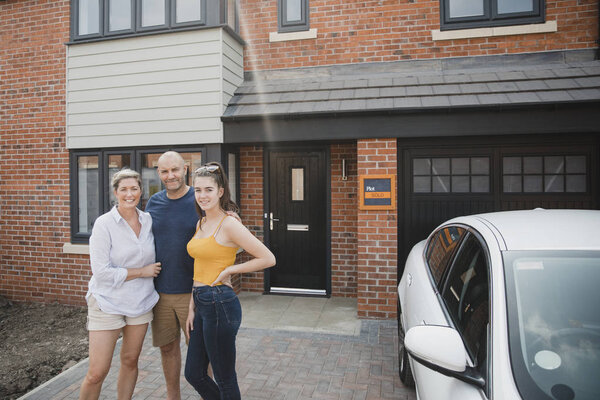 Portrait of a family with one child outside of their new home.
