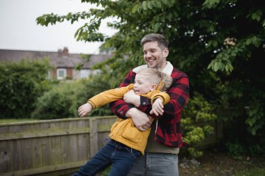 Küçük bir çocuk babası ile eğleniyor. Baba oğlu onun Gövde tutan ve onun etrafında gülerek ve gülümseyerek sallanan.