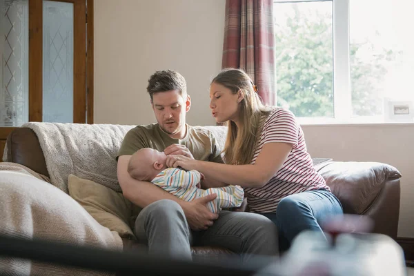 남편과 아내는 그들의 신생아 거실에서 소파에 남자는 아기를 들고와 아기를 — 스톡 사진