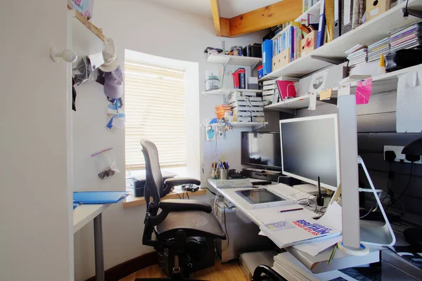 ホーム オフィスで散らかった机のショット 部屋は小さく 雑然と 机の上は つのコンピューターのモニターとオフィス用品 — ストック写真