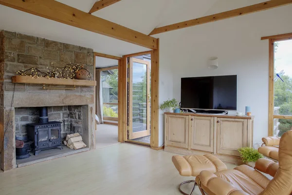 一个温暖和舒适的客厅内部的宽视角拍摄 在图像的左侧是一个壁炉与木柴附近 右边是一个真皮椅子 鉴于现代电视 — 图库照片