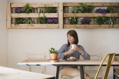 Olgun kadın küçük bir kafede bir masada bir fincan kahve ile oturuyordu. O pencereden dışarı bakarak ve huzur ve sessizliğin tadını.