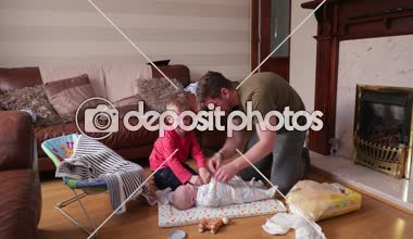 Küçük bir çocuk babası küçük kardeşi onun nappy değişiklikten sonra tespitleme ile yardım. Onun bebek mat küçük çocuklar bebek bezi değiştirme oturma odasında onlar.