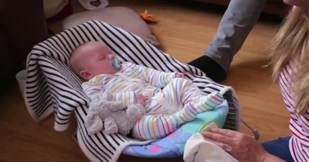 婴儿睡在他的婴儿保镖 而爸爸摇摇他和他的妈妈坐在他旁边 — 图库视频影像