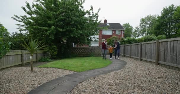 家庭在花园里散步 小男孩被他的胳膊在空中晃来晃去 — 图库视频影像