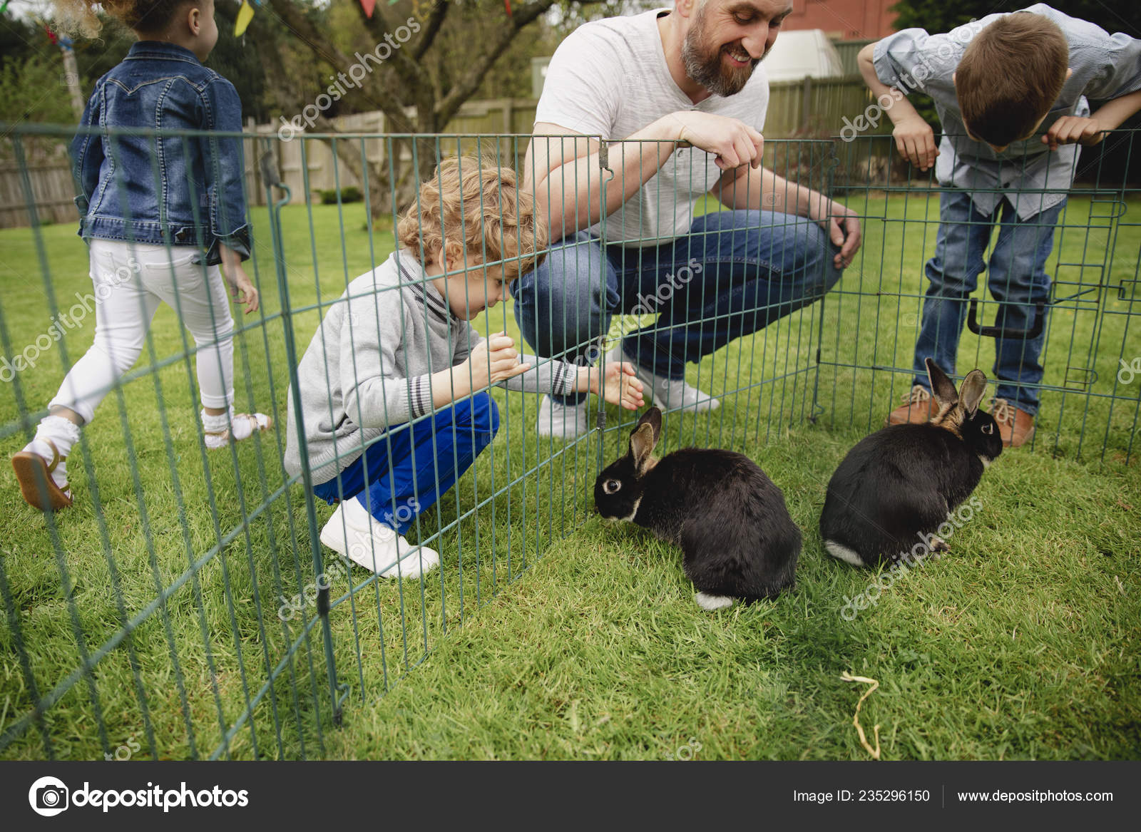 Group Children Kneeling Outdoors Next Rabbit Pen Trying Pet