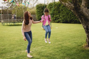 Küçük bir kız iken onu annesine yardımcı olur ve onu iter bir salıncak üzerinde dışında oynarken. O eğleniyor ve kendini zevk. 
