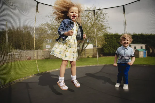 Küçük Kız Oğlan Dışarıda Bir Trambolinde Oynuyorlar Eğleniyorlar Eğleniyorlar — Stok fotoğraf